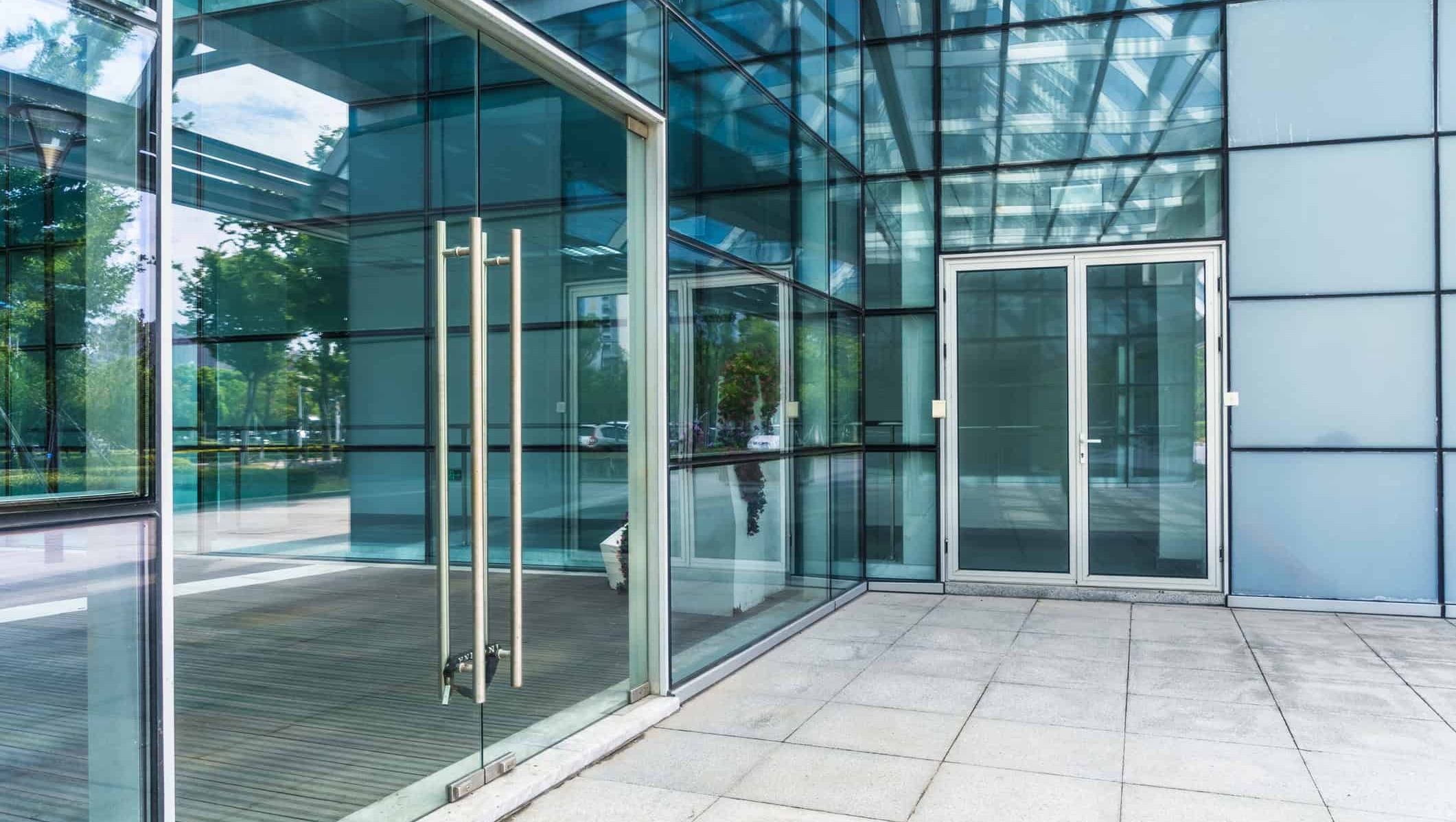 Moderne inngangsparti med store glassflater, glassdører og fasade i stål og aluminium.